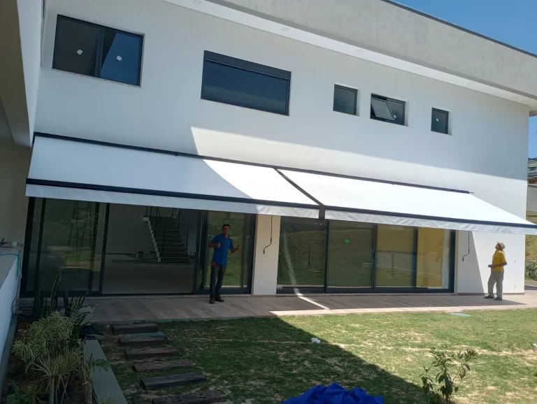 Toldo articulado de braço dobrável cobrindo área gourmet